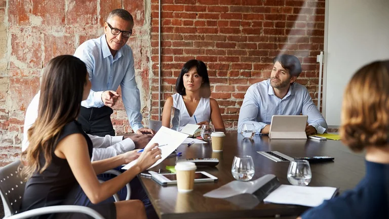 Man standing up talking to a table of seated people