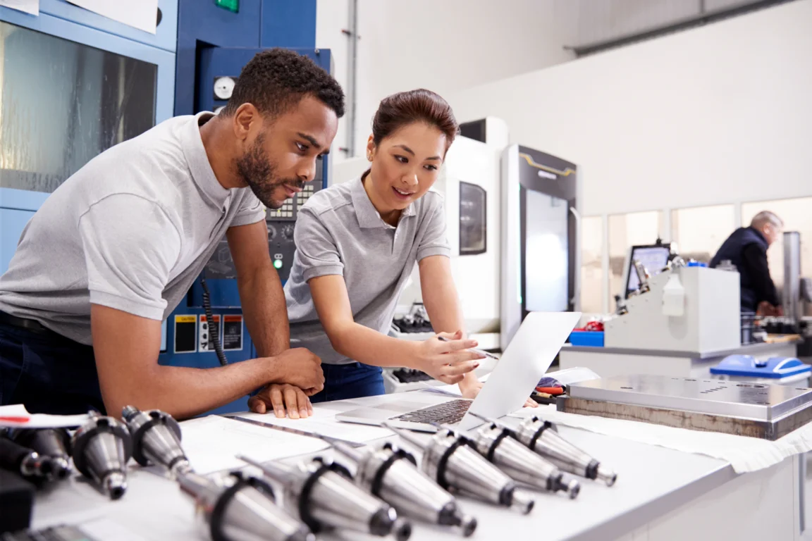 Two manufacturers examine computer in factory