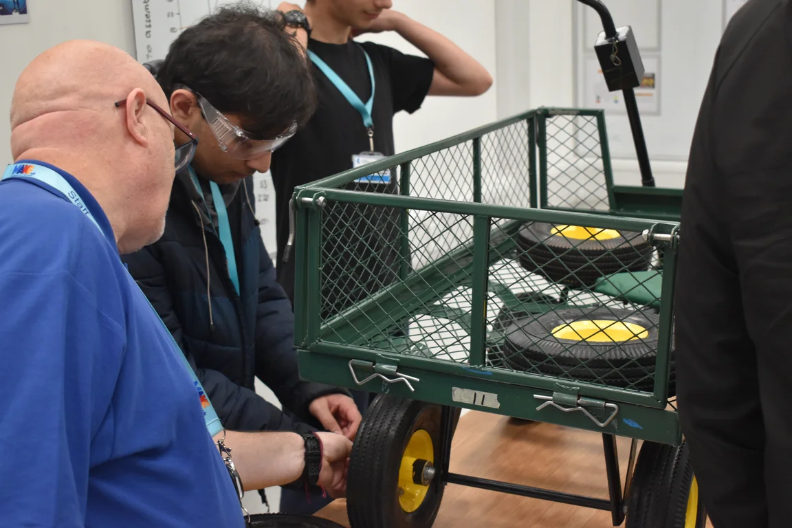 Make UK Tech Hub, demonstrator helps student fix wheel to trolley