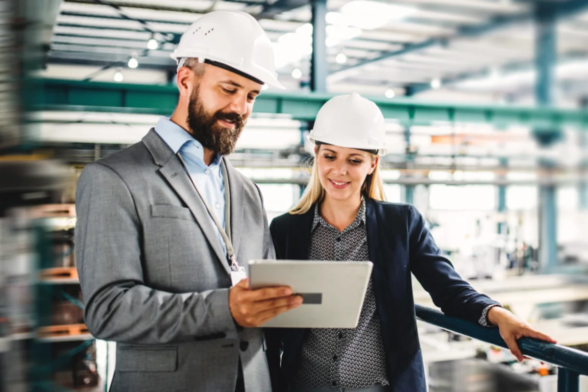 Two factory office workers looking at data on an ipad/ tablet